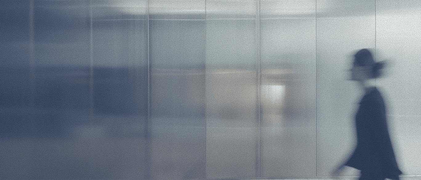 Blurred figure walking through a modern, glass-walled office space, conveying security and professionalism